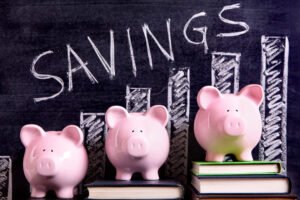 three-pink-piggy-banks-standing-books-blackboard-with-savings-chart-scaled.jpg